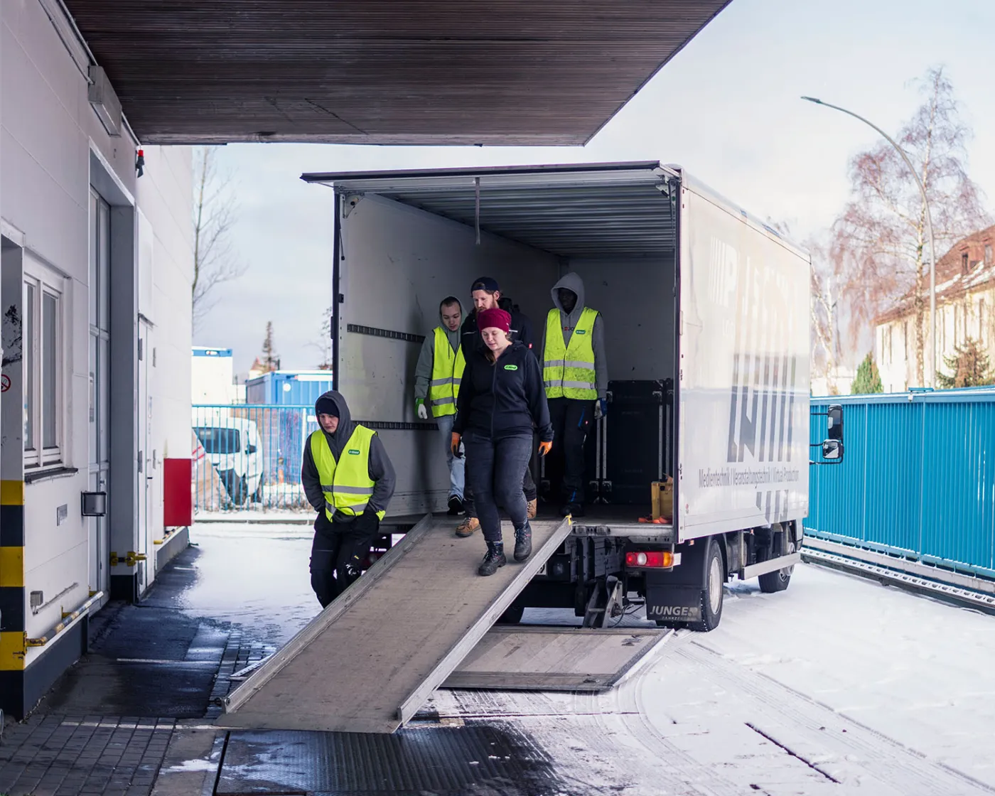 Eventhelfer beim Entladen Crew in Warnwesten entlädt einen Lkw über eine Rampe