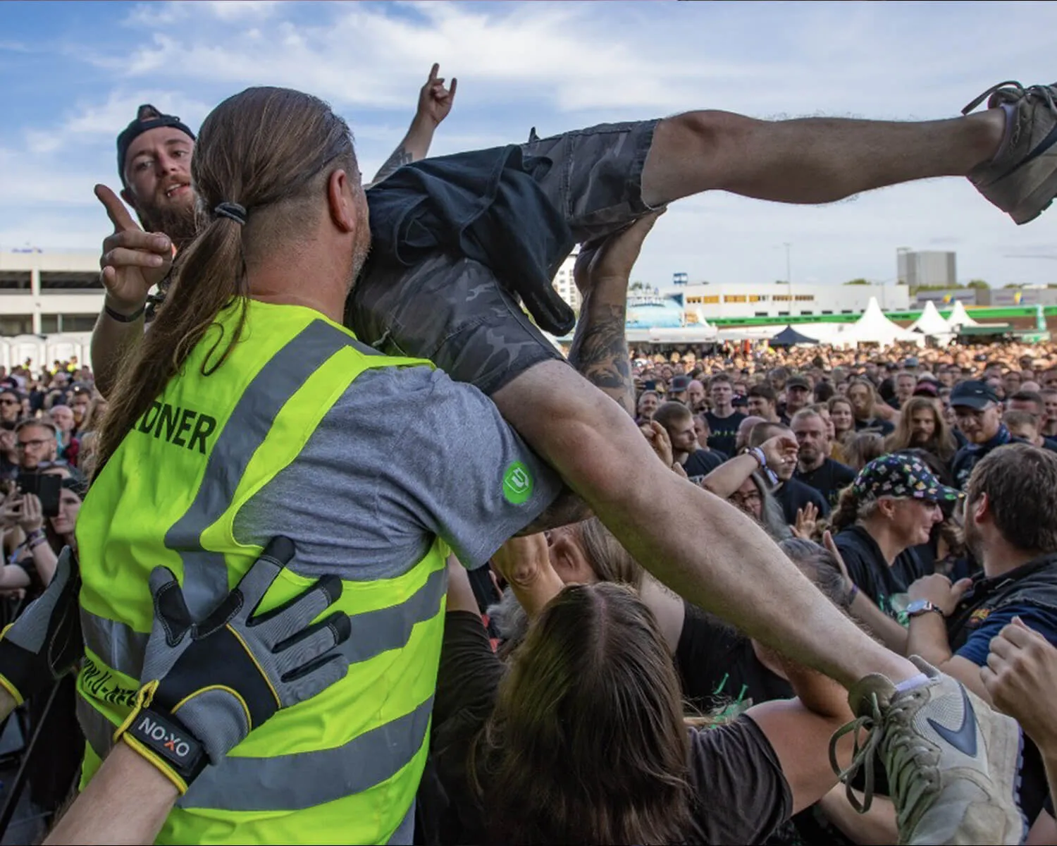 Ordnungsdienst im Bühnengraben Ordner in gelber Weste nimmt einen Crowdsurfer vor der Bühne in Empfang
