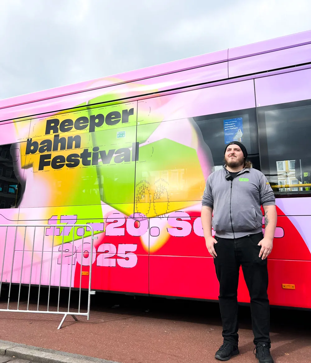 Mitarbeiter steht vor einem Bus im Design des Reeperbahn Festivals