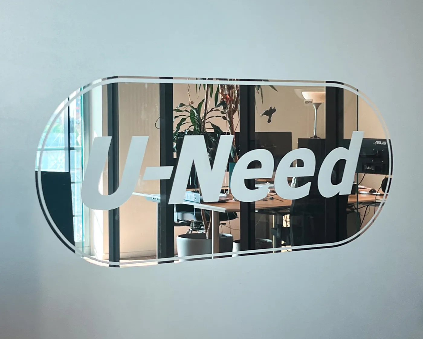 U-Need Büro U-Need Schriftzug auf einer Glaswand, dahinter ein Büro